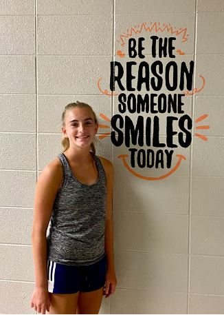 Sophomore Ashlyn Loomis stands in front of a mural she helped create. This is one of two murals in the bathroom.